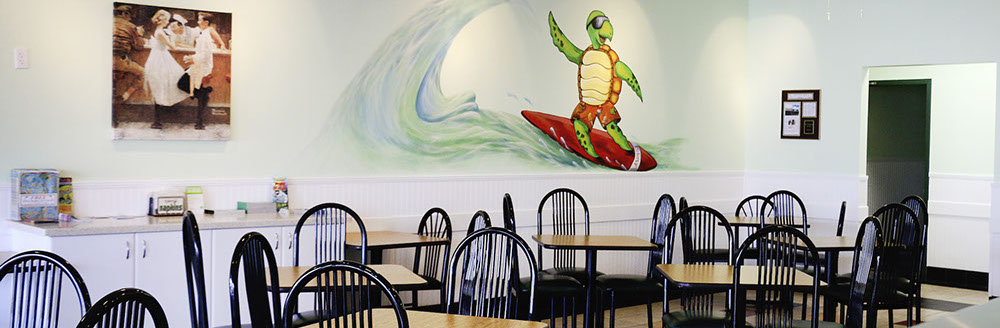 tables and chairs with cartoon surfing turtle mural on wall
